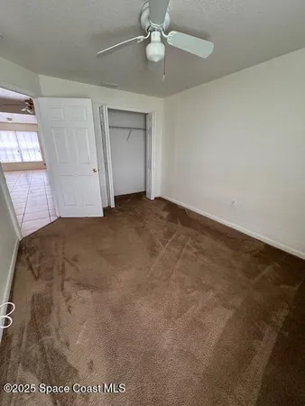 an empty room with a ceiling fan and window