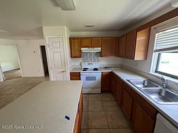 a kitchen with granite countertop a sink stove and refrigerator