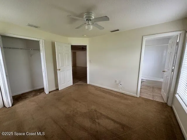 an empty room with closet and a ceiling fan