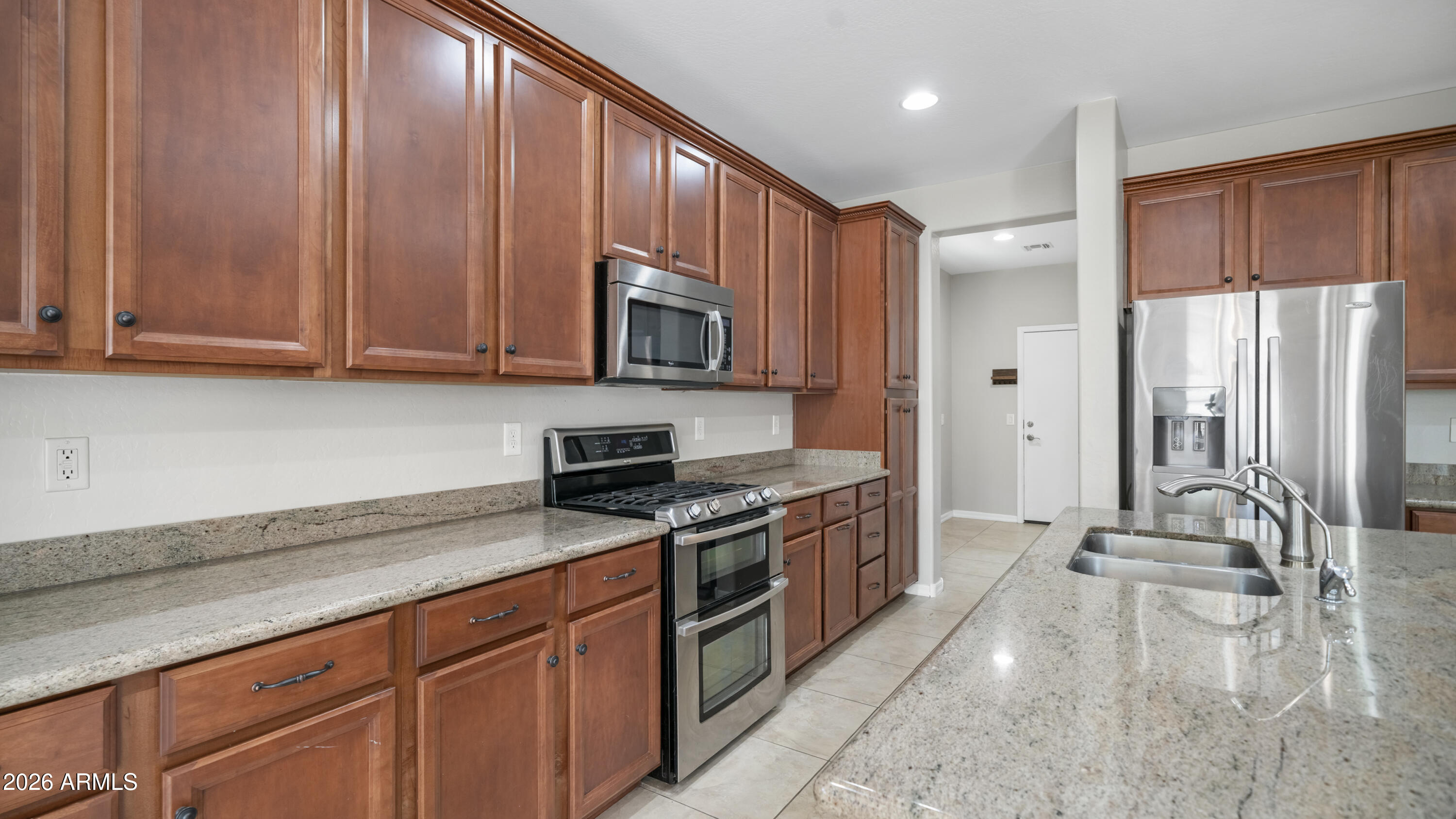 16159 West Granada Road Goodyear, AZ 85395 - Photo 15 of 41 a kitchen with stainless steel appliances granite countertop a stove a sink and a microwave