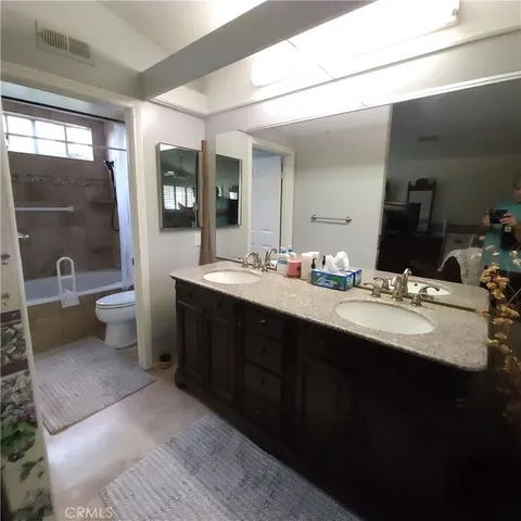 a bathroom with a double vanity sink a toilet and mirror