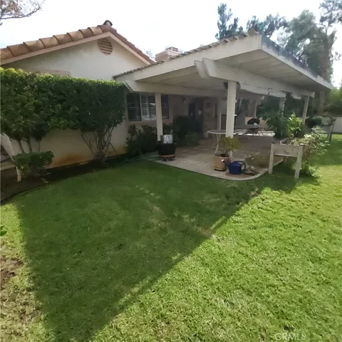 a view of a patio with table and chairs potted plants and large tree