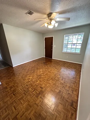 an empty room with windows and fan