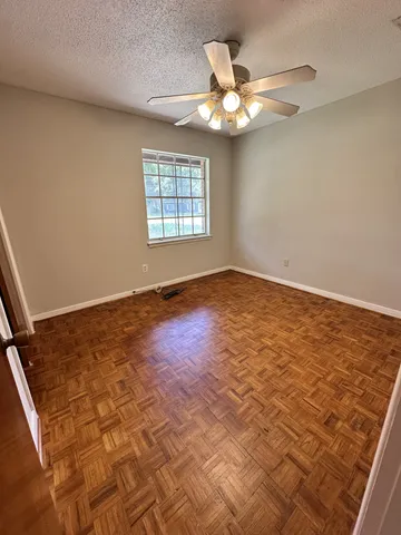 an empty room with a chandelier fan and windows