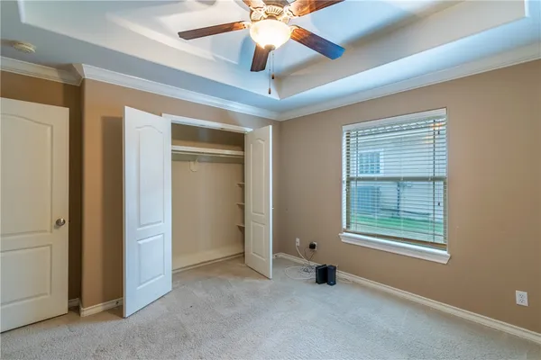 an empty room with chandelier fan and windows