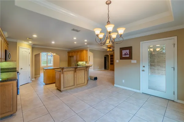 a view of a kitchen with kitchen island granite countertop a refrigerator a oven a counter top space and a chandelier