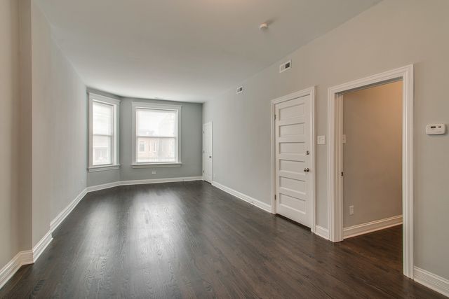 an empty room with wooden floor closet and windows