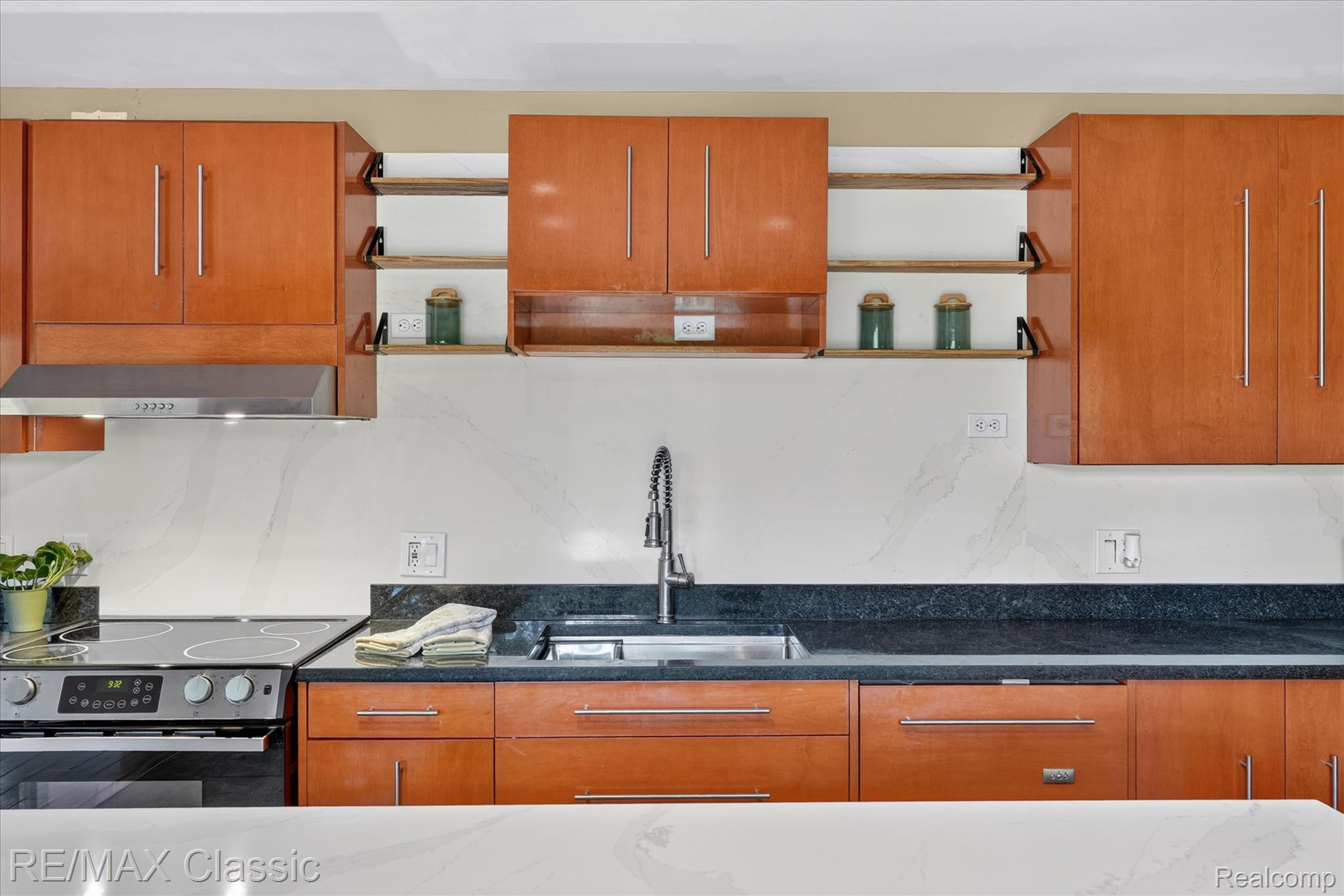 12189 Gage Road Holly, MI 48442 - Photo 14 of 69 Kitchen featuring wood-finish cabinetry, dark stone countertops, a stainless steel sink with a gooseneck faucet, a white tile backsplash, and a stainless steel electric range with an overhead vent hood
