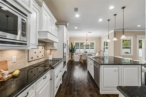 an empty room with wooden floor chandelier fan and windows