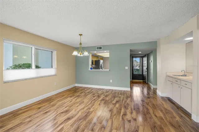 a view of an empty room with window and wooden floor