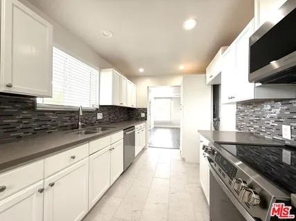a kitchen with granite countertop a sink stove and cabinets