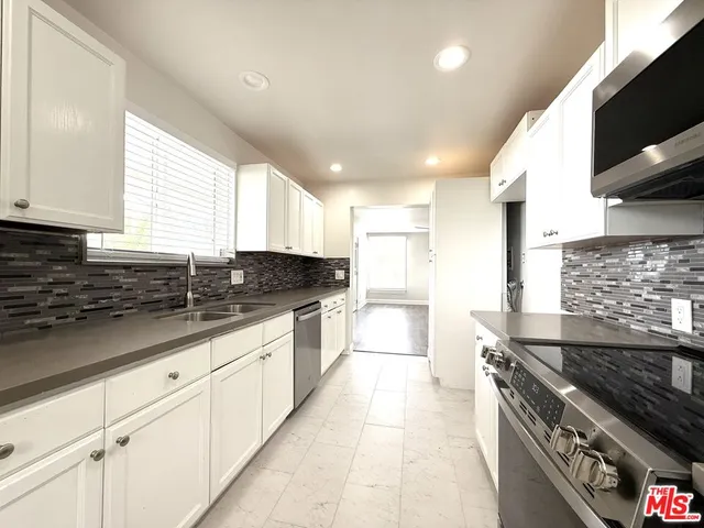 a kitchen with granite countertop a sink stove and cabinets