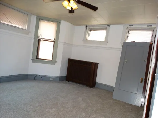 an empty room with windows and fan