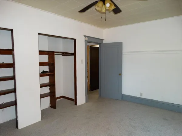 an empty room with closet and a ceiling fan