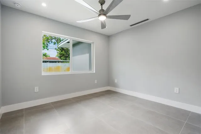 an empty room with windows and ceiling fan