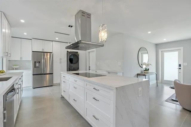a large kitchen with stainless steel appliances a large counter top and a refrigerator