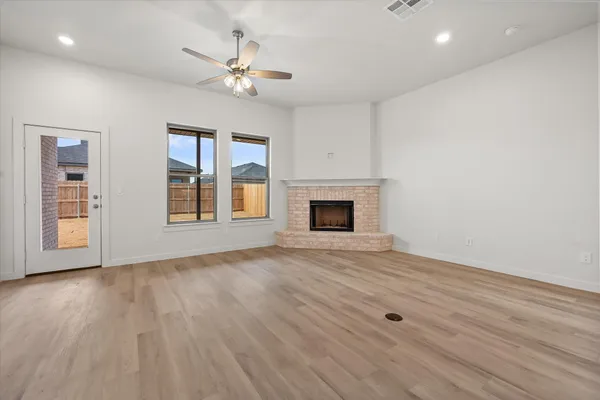 a view of an empty room with wooden floor fireplace and a window