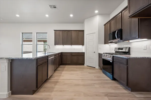 a large kitchen with stainless steel appliances and a large counter top