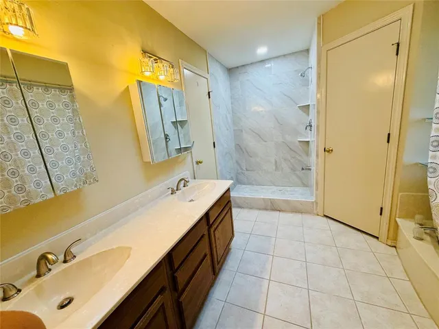 a bathroom with a tub sink a mirror a shower and a sink