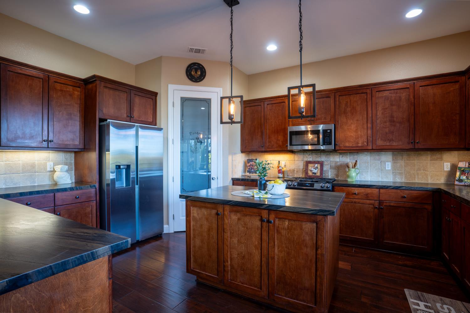 3388 Sudbury Road Cameron Park, CA 95682 - Photo 9 of 47 a kitchen with stainless steel appliances granite countertop a refrigerator a sink dishwasher a stove and a refrigerator with wooden floor
