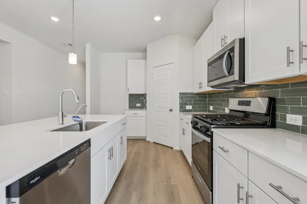 a kitchen with stainless steel appliances granite countertop a sink stove oven and white cabinets