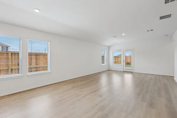 an empty room with wooden floor and windows