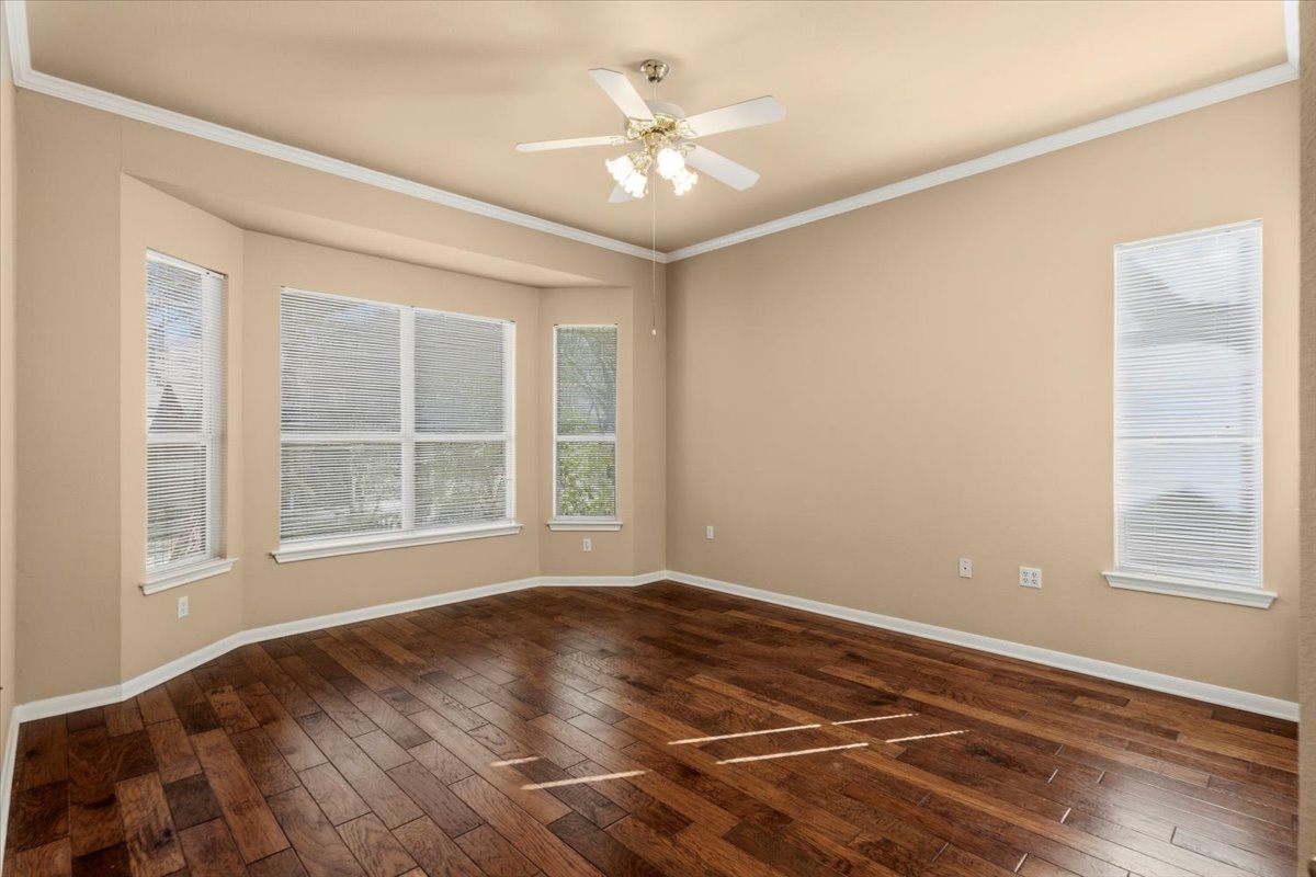 211 Whispering Wind Drive Georgetown, TX 78633 - Photo 7 of 33 Unfurnished room with crown molding, dark wood finished floors, and a ceiling fan