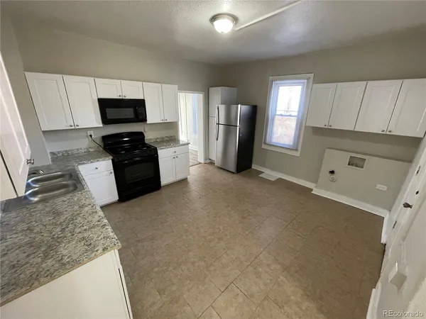 a view of a kitchen with fridge and wooden floor