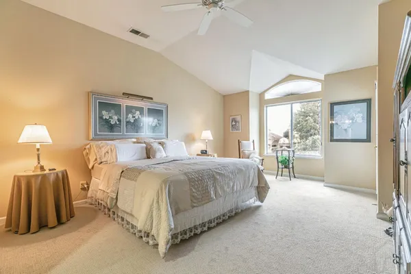 a spacious bedroom with a bed and a lamp