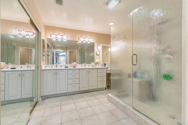 a bathroom with a double vanity sink mirror and shower