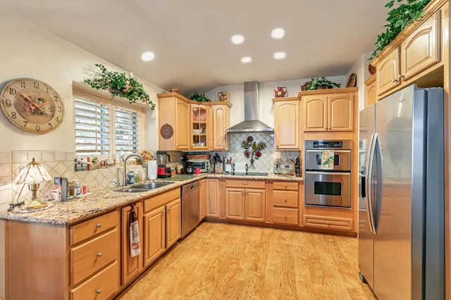 a kitchen with stainless steel appliances granite countertop a stove a sink and a refrigerator