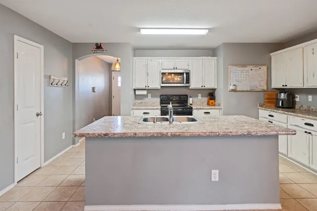 a kitchen with kitchen island granite countertop a sink and white cabinets