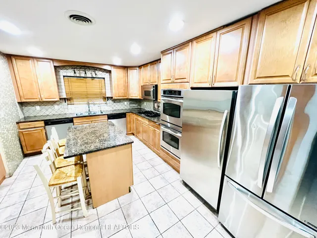 a kitchen with granite countertop a refrigerator a stove a sink and cabinets