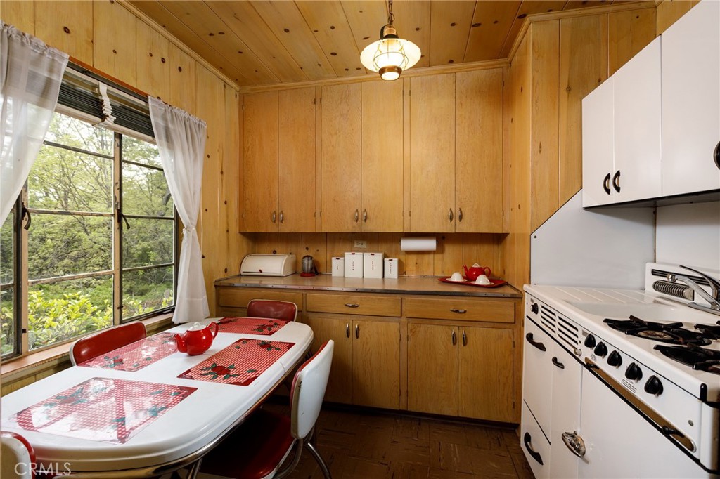28641 North Shore Road Lake Arrowhead, CA 92352 - Photo 66 of 75 a kitchen with a stove a sink a dining table and chairs