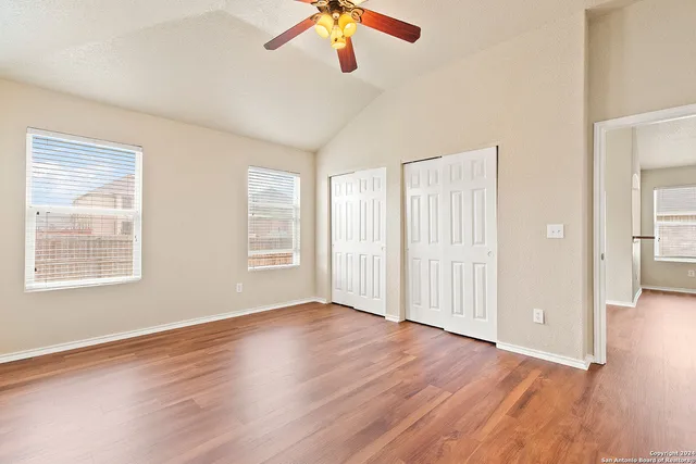 a view of an empty room with wooden floor and a window
