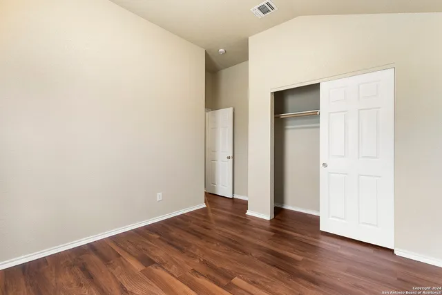 an empty room with wooden floor & closet area