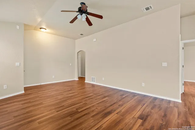 a view of empty room with wooden floor and ceiling fan