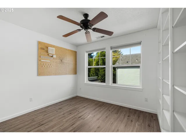 a view of an empty room with a window and wooden floor
