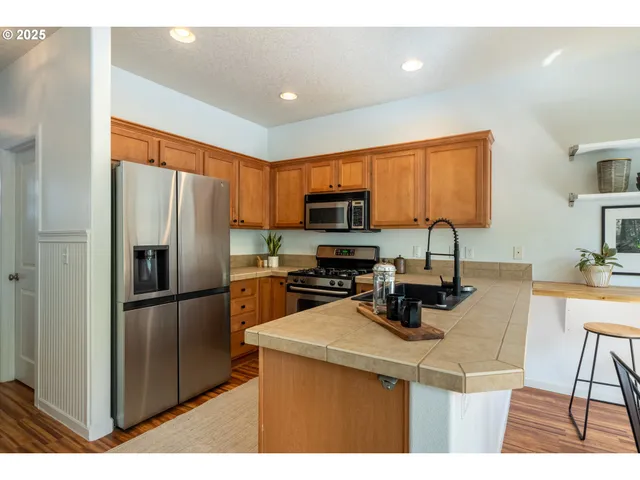 a kitchen with stainless steel appliances a refrigerator a sink a stove a microwave a counter top space and cabinets