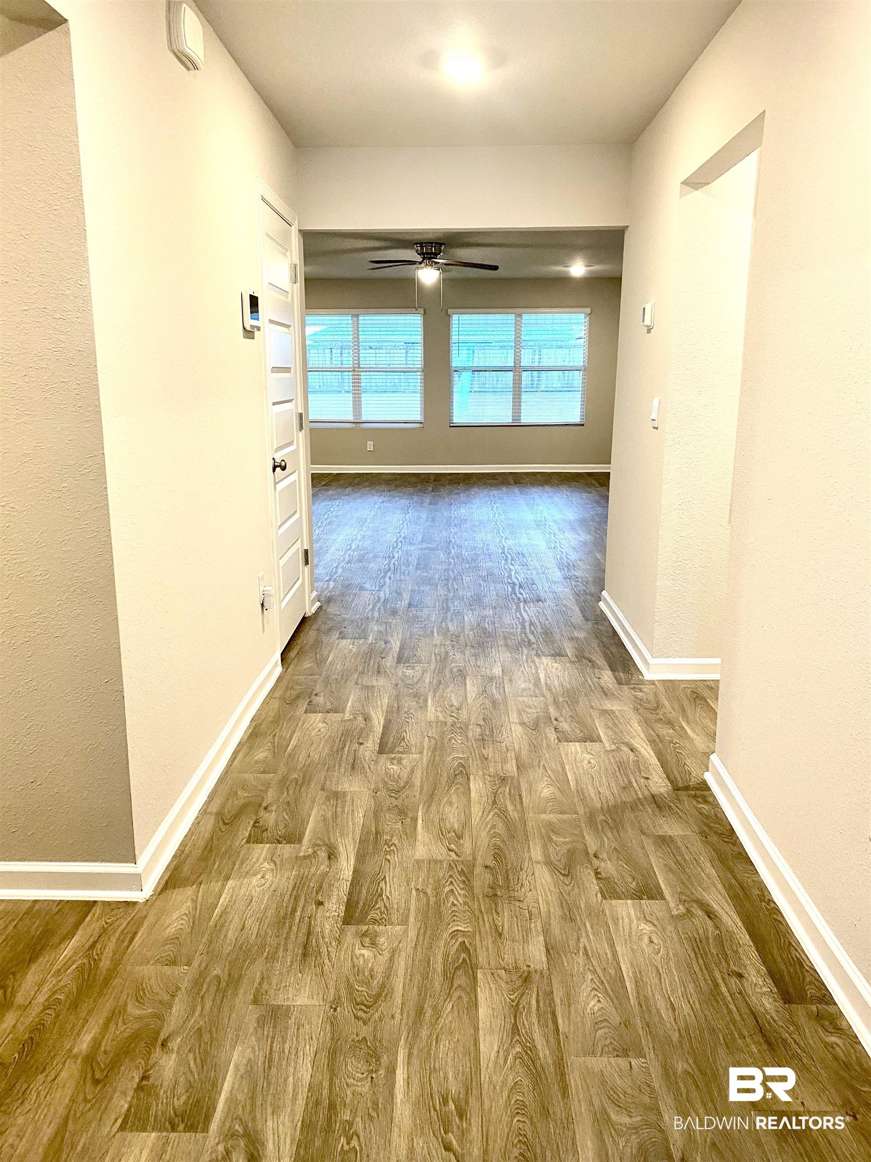 Hallway featuring light wood finished floors and a textured wall