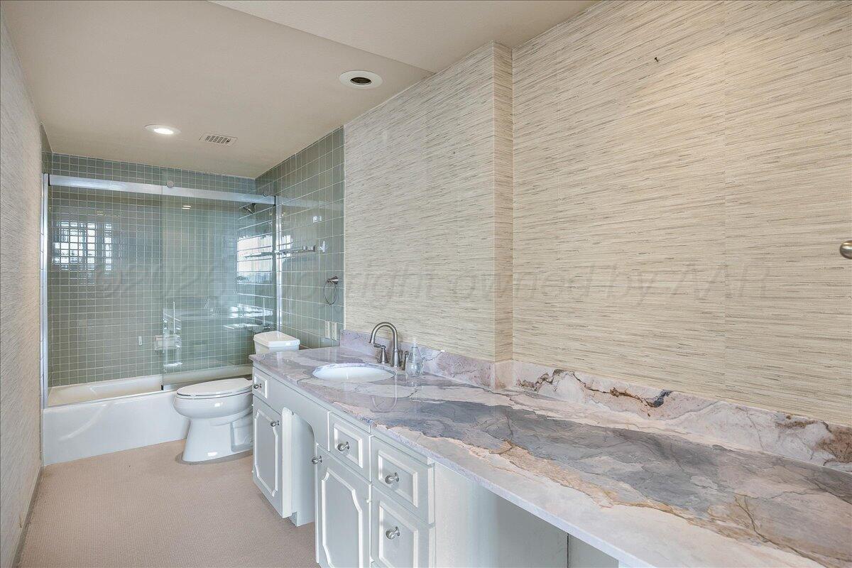2028 South Austin Street, Unit 907 Amarillo, TX 79109 - Photo 24 of 39 a bathroom with a granite countertop sink a toilet a mirror and shower
