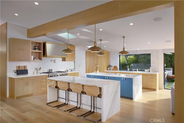 a kitchen with stainless steel appliances kitchen island granite countertop a stove a sink a refrigerator and chairs