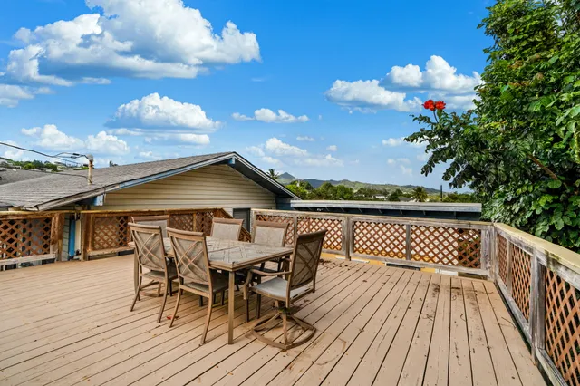 a view of a roof deck with table and chairs with wooden floor and fence