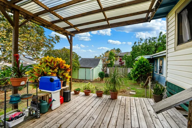 a roof deck with table and chairs and potted plants with wooden floor