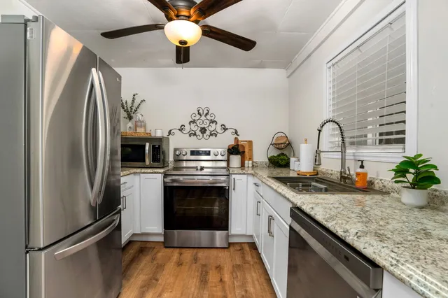 a kitchen with stainless steel appliances granite countertop a refrigerator a stove and a sink