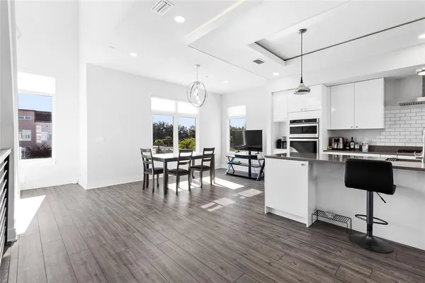 a kitchen with stainless steel appliances kitchen island granite countertop a table chairs refrigerator and microwave