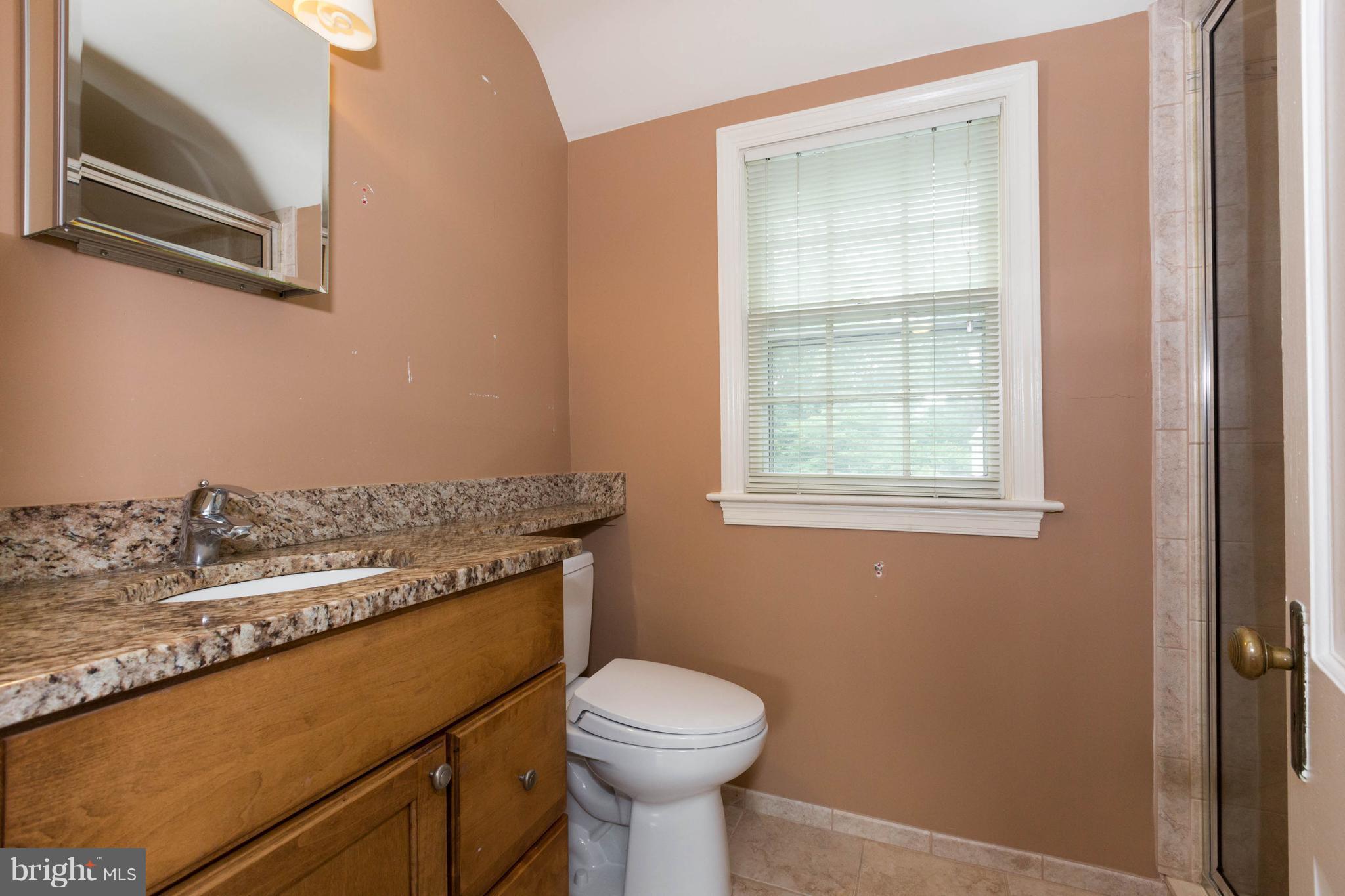9600 Sutherland Road Silver Spring, MD 20901 - Photo 18 of 30 a bathroom with a granite countertop sink a toilet and a window