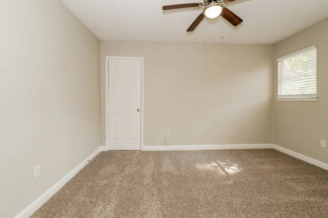 an empty room with a window and a ceiling fan