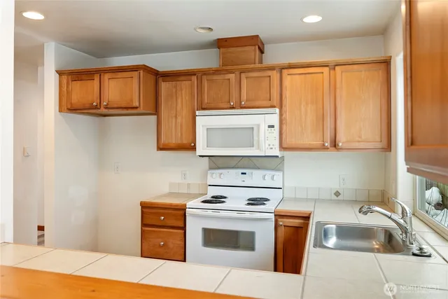 a kitchen with stainless steel appliances granite countertop a stove a sink and a microwave