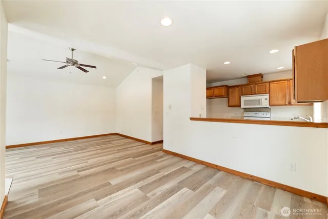 a view of kitchen and empty room with wooden floor